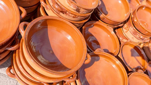 Stacks of glazed terracotta dishes bask under the sun.