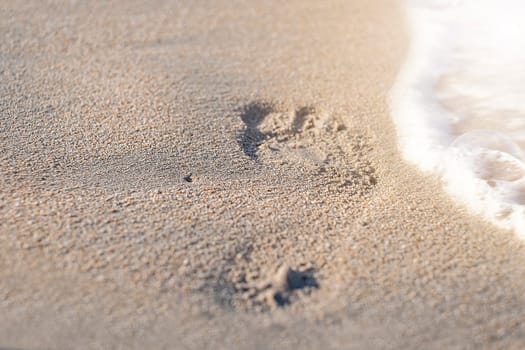 Footprint with golden sand. Beach, wave and footstep on sunny day.
