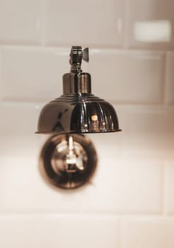 old vintage shiny lamp hangs on the white brick wall of the interior