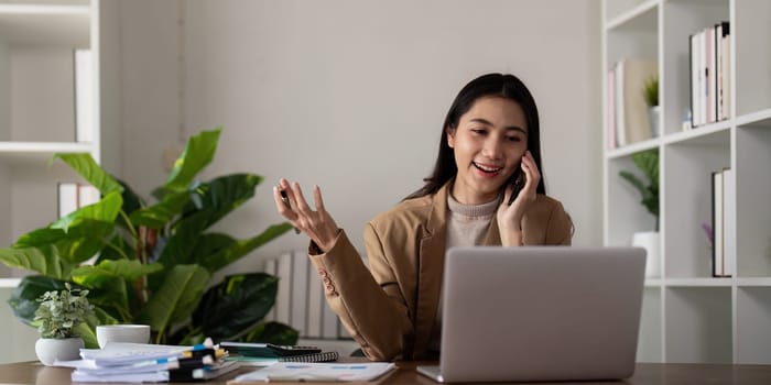 Work from home. Businesswoman using laptop computer and smartphone in her room. Eco friendly businesswoman working on desk, freelance, green room area, sustainable lifestyle concept.