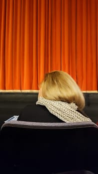 spectator in the theater, blonde woman head, red curtain. High quality photo