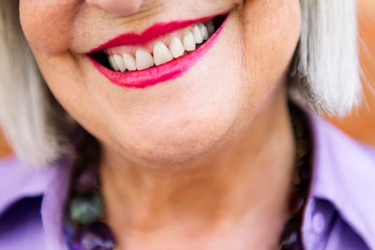 detail of toothy smile of a beautiful unrecognizable senior woman, concept of elderly people happiness and active lifestyle