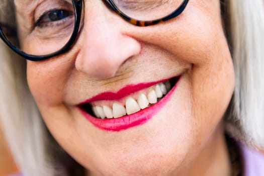 close up detail of toothy smile of a beautiful senior woman, concept of elderly people happiness and active lifestyle