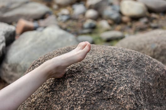 Rest on the sea. A naked female leg lies on a large stone on the sea coast.