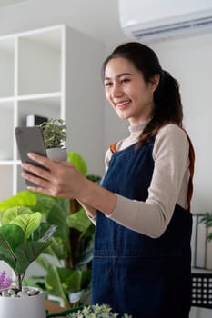 The concept of eco friendly housing, plant care and gardening. Relax home gardening. Gardener woman asian take a selfie with plant. Smiling woman takes care of plant.