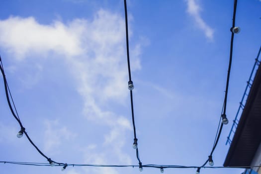 Several electric glass lamps in a garland against the evening blue sky.