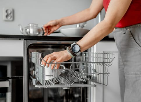 Young Woman Takes Out Clean Dishes From Dishwasher In Close-Up Shot