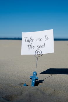 TAKE ME TO THE SEA text on paper greeting card in anchor paper holder and starfish seashell summer vacation decor. Sandy beach sun coast. Holiday concept postcard. Getting away Travel Business concept