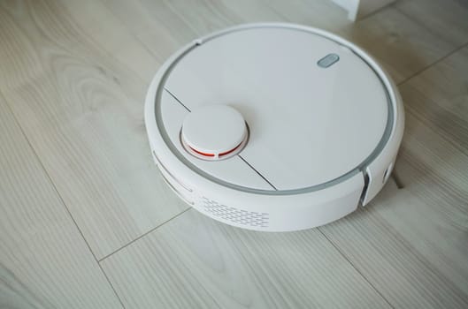 white robot vacuum cleaner cleaning the apartment