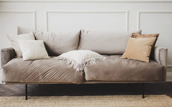 gray sofa with pillows against a white, empty wall in a simple living room interior