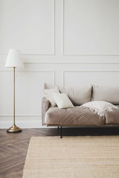 Real photo of the bright spacious interior of the living room with wooden floors and gray carpet and a sofa