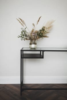 Stylish metal table with flowers in a light interior