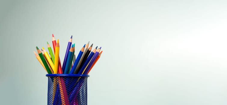 Stack of colorful textbooks and a glass of bright pencils on a white background, Concept of education, training, School tools, workspace, copy space, Banner design education concept background.