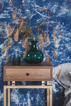 beautiful decorative flowers in a vase on the shelf. stylish bedroom interior in blue tones