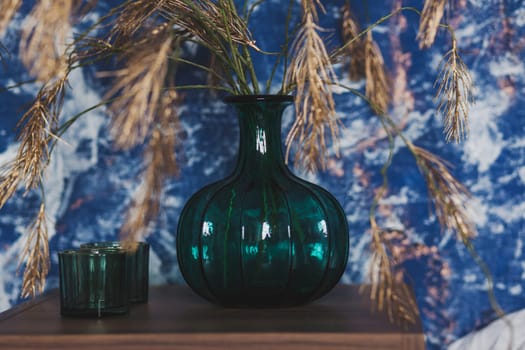 Home interior decor in blue colors glass jar with dried flowers, vase on the table
