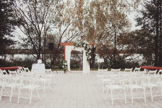 Wedding arch decorated with cloth and flowers outdoors. Beautiful wedding set up