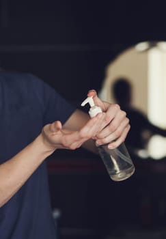 close-up mens hands using wash hand sanitizer gel pump dispenser.