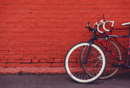 two vintage bicycles parking against red brick wall. copy space