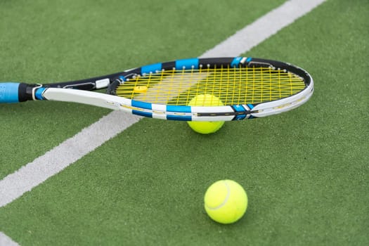 Tennis ball and racket on the ground of sunny outdoor grass tennis court. Summer, healthy lifestyle, sport and hobbies. High quality photo