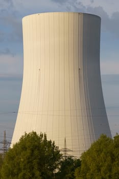 A nuclear power plant stands tall in the background while trees add a touch of nature in the foreground.