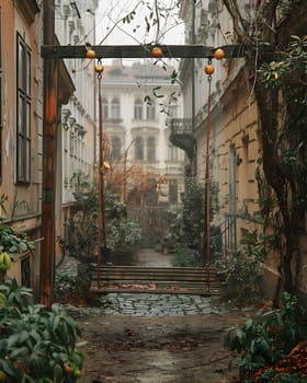 A swing hangs in the middle of an alleyway, surrounded by buildings, vegetation, and a wooden fixture. The urban landscape contrasts with the peaceful road surface