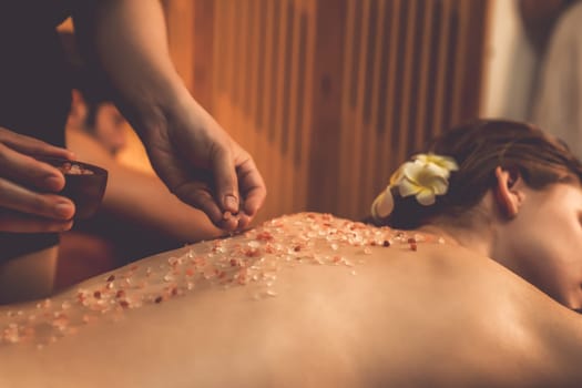 Closeup couple customer having exfoliation treatment in luxury spa salon with warmth candle light ambient. Salt scrub beauty treatment in Health spa body scrub. Quiescent