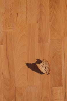 A Piece Of Bread with shadow On A Wooden cutting board.