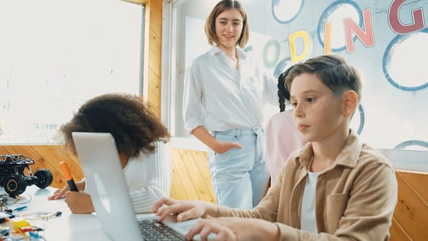 Smart teacher teaching and looking student using laptop at classroom. Professional instructor explained about programing engineering code or prompt while studying and learning program. Erudition.