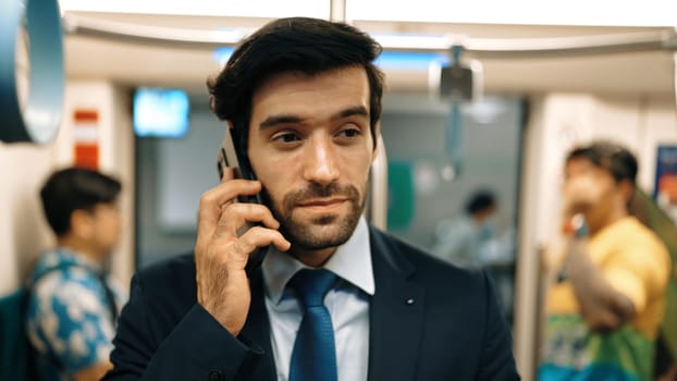 Smart business man phone calling to project manager while standing in train. Professional male leader talking to investor about marketing plan by using phone with blurring background. Exultant.