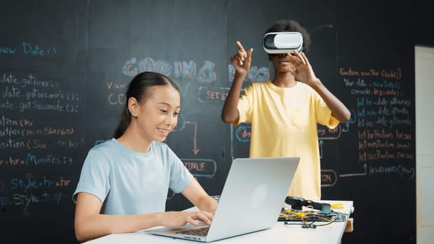 African boy wear headset to enter in metaverse while young beautiful academic student writing, coding, programing system on table with laptop or device placed. innovative education. Edification.