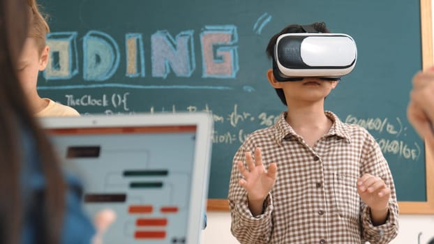Energetic child wearing Vr headset while enter virtual world at classroom. Student programing system while generated AI to code engineering prompt software while boy fixing electronic board. Pedagogy.