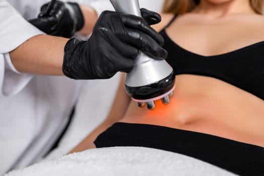 RF body cavitation lifting procedure to reduce fat in belly to young woman in a beauty salon