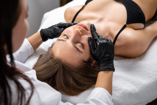 Close up of young woman getting face spa massage treatment at beauty salon. Skin and body care concept.