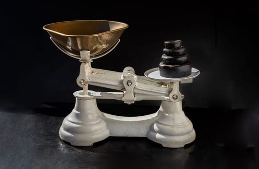 Old obsolete manual weighing scales and Iron Brass Tray with set of cast iron weights. Classic weight scale Isolated on dark background, Antique balance scales, Space for text, Selective Focus.