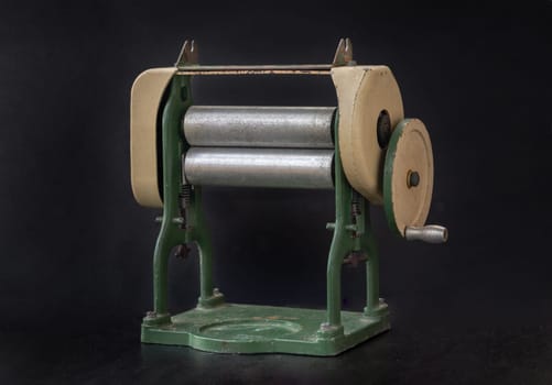 Antique pasta maker with hand crank on dark background. Vintage Pasta machine, Space for text, Selective focus.