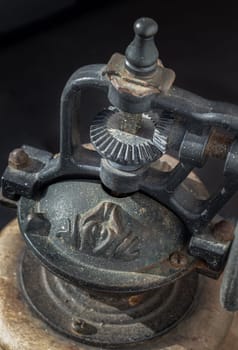 Detail of Antique coffee bean original grinder metal shake wheel with hand crank on dark background. Close-up of Old original coffee grinder, Space for text, Selective focus.