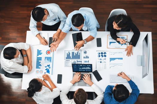 Top view analyst team utilizing BI Fintech to analyze financial data at table in meeting room. Analytic BI dashboard power on paper for business insight and strategic marketing planning. Prudent