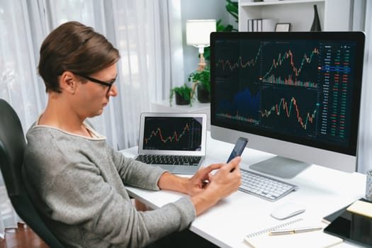 Smart stock investors pointing on screen with smartphone for market stock exchange along with laptop screen in highest dynamic investment rate, focusing data planning at modern workplace. Pecuniary.