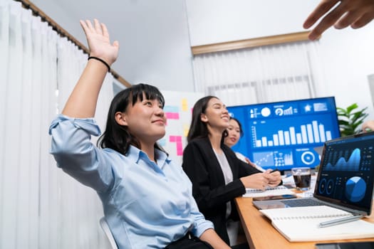 Diverse ethnic group of analyst team actively engage in business meeting, demonstrate their expertise by raise hand, asking insightful questions with TV screen show data analysis dashboard. Habiliment