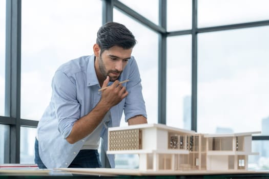 Smart civil architect engineer looking while planing design house construction with blueprint, house model and architectural equipment. Designer measuring and inspecting house model. Design. Tracery.