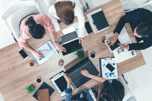 Top view of businessman executive in group meeting with other businessmen and businesswomen in modern office with laptop computer, coffee and document on table. People corporate business team uds