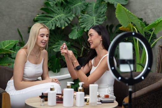 Two beautiful content creator making natural beauty and cosmetic tutorial on green plant garden video. Beauty blogger showing how to beauty care to social medial audience using selfie stick . Blithe