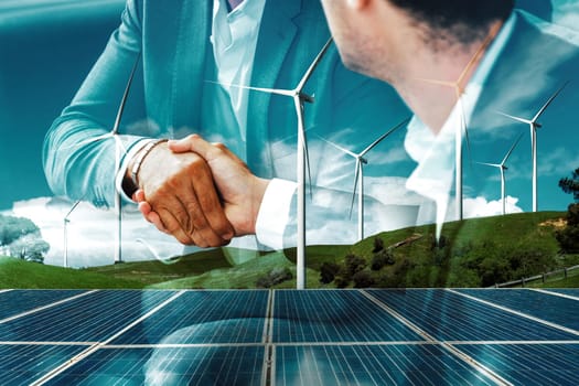 Double exposure graphic of business people handshake over wind turbine farm and green renewable energy worker interface. Concept of sustainability development by alternative energy. uds