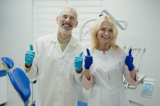 Male and female dental doctors wearing face sitting at his clinic. High quality photo