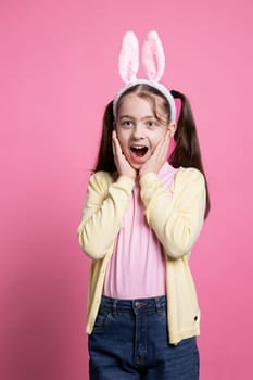 Enthusiastic positive kid acting surprised by easter gifts in studio, feeling cheerful with her presents and enjoying april festivity. Young optimistic child getting excited about spring celebration.