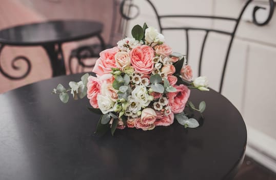 Wedding bouquet of their roses and eucalyptus on the table in the cafe