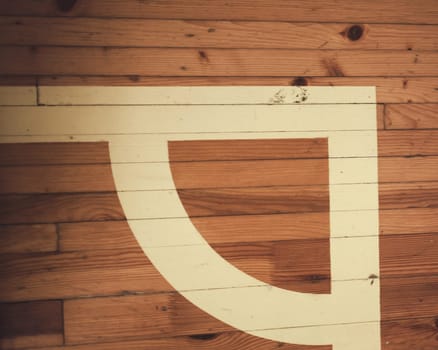 corner and white line. Worn out wooden floor of sports hall with marking lines