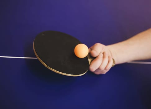 hand with a table tennis racket and a ball. serve in ping pong