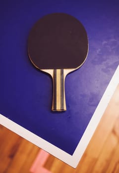 tennis racket on the corner of the blue table. the game of ping pong