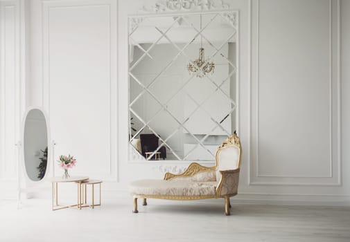 Old fashioned sofa in classic light interior with big mirror